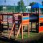 Square Play castle with slide in a playground, featuring climbing ladders, a bridge, and a tube slid