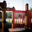 Square Play castle with slide for kids, wooden frame with red rails.