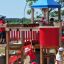 Square Play castle with slide in outdoor playground, children playing.