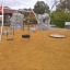 Playground equipment Double Swing in a sandy park area with tire and regular seat.
