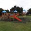 Playground equipment Tritowers castle with slide in park setting.