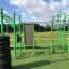 Outdoor fitness equipment New Age Fit placed on a green grassy area under a partly cloudy sky.