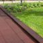 Rubber Tiles 55 playground safety flooring in dark red next to green grass and plants