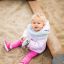 A toddler sitting in the Villa Maxi sandbox with a playhouse.