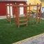 Chimpanzee wooden playhouse with climbing ladders and bars on green artificial grass.