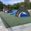 Dolphin Slide on playground with green rubber flooring and trees in background