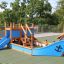 Small Ship with Dolphin playground structure with blue accents and slide.