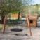 Wooden playground swing set BNS Single Swing Robinia 2 Posts next to a small wooden playhouse.