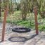 BNS Single Swing Robinia 2 Posts playground swing made of wood and black tire seat in a park.