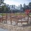 Outdoor playground structure 'Poison Ground' with wooden climbing elements and a red slide on a sand