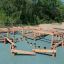 Poison Ground wooden multi-level playground structure with balancing beams and steps.