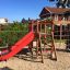 Climbing Kiosk (Wide Slide) with red slide in a playground.
