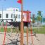 Mast climbing net in playground with red flag and sandbox.