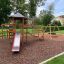 Six Angle with Suspension Bridge single slide playground set in a park with mulch surface