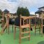 Playground Explorer castle with slide made of wood and black panels on green surface.