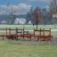 Outdoor wooden playground Course with benches and climbing elements on grassy area.