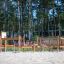 Course wooden playground climbing and balancing structure in sandy area with forest background