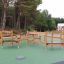 Wooden playground obstacle course with climbing ropes and platforms.