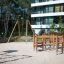 Course wooden playground climbing structure with ropes and platforms in sandy area.