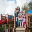 Children playing on a large wooden playground structure with a slide.