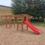 Activity Center with Slide on a sandy playground with climbing elements and red slide
