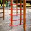 Wooden Activity Center with Slide featuring red climbing rails in a sandy playground.