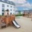 Rubik Modern Nature wooden playhouse with slide on sandy playground with residential buildings in th