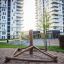 Wooden climbing structure Atakama on a playground in front of tall residential buildings.