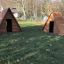 Two wooden Small House play structures in a grassy outdoor area.