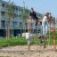 Children playing on V-shape Net wooden playhouse in a park.