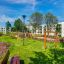 ALT: Modern playground with V-shape Net wooden playhouse in a residential area.