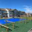 V-shape Net wooden playhouse in a modern playground with residential buildings in the background
