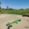 Single Seesaw in a sandy playground with a grassy hill in the background.