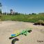Single Seesaw in a sandy playground with a grassy hill in the background.