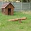 Nature Playhouse in a grassy backyard with a wooden seesaw.