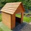 Nature Playhouse made of wooden planks in a grassy backyard setting.