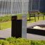 Oxford bin in a modern park setting with benches and greenery.