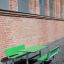 Green Table & Bench HPL set against a brick wall outdoors.