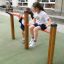 Two girls playing on the Somersault Double fitness bars in a playground.