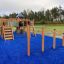 Wooden playground structure Somersault Triple on blue safety surface in an outdoor setting.