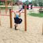 Child hanging upside down on the Somersault Triple in a playground.