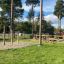 Outdoor playground featuring the Somersault Triple with wooden posts and balancing beams amidst gree