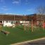 Somersault Triple playground equipment set on a green artificial turf in front of a building