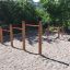 Outdoor playground with Somersault Triple wooden climbing equipment and red bars.