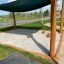 Square sandbox with wooden posts and sun shade.