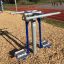 Outdoor Double Ski Trainer exercise equipment on woodchip ground near a running track.