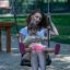 Mother and child sitting together on Safety Seat Single Swing in playground.