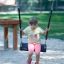 Child sitting on Safety Seat Single Swing in playground setting