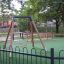 Safety Seat Single Swing on a playground with green artificial turf