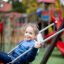 Child on Safety Seat Single Swing in playground.